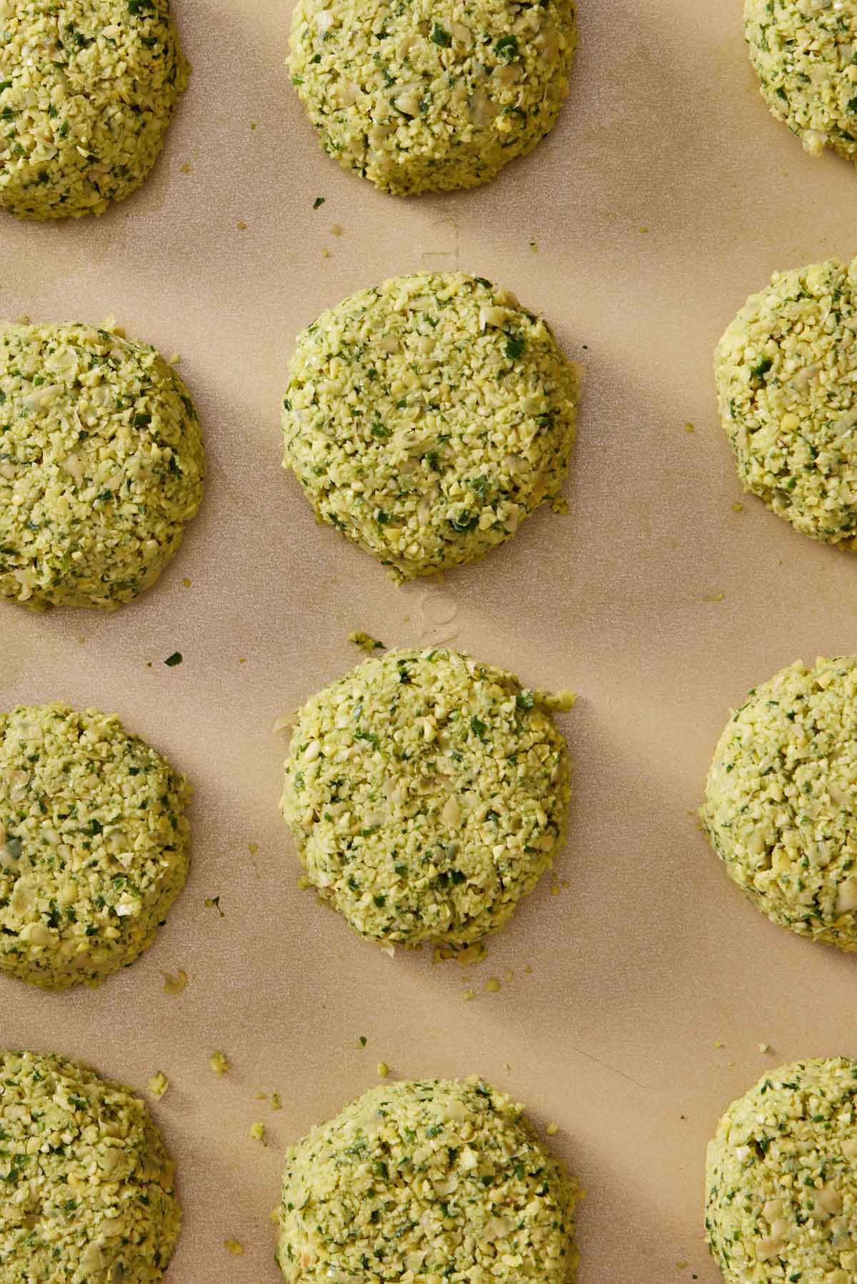 Overhead view of multiple air fryer falafel before being cooked on a sheet pan in a single layer.
