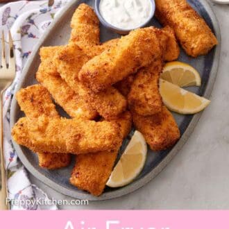 Pinterest graphic of a platter of air fryer fish sticks with lemon wedges and a bowl of tartar sauce.