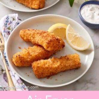 Pinterest graphic of a plate with three air fryer fish sticks and lemon wedges.