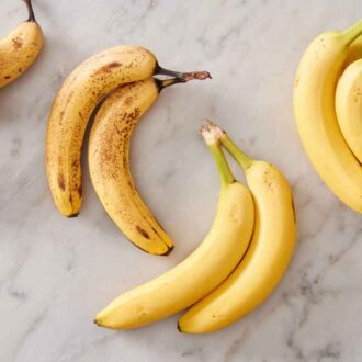 Multiple bundles of bananas on a marble surface.