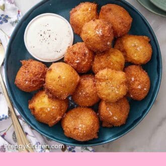 Pinterest graphic of an overhead view of hush puppies with a small bowl of dipping sauce.