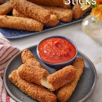 Pinterest graphic of a plate with mozzarella sticks, one torn opened, with a bowl of marinara sauce. A platter of more mozzarella sticks in the background.