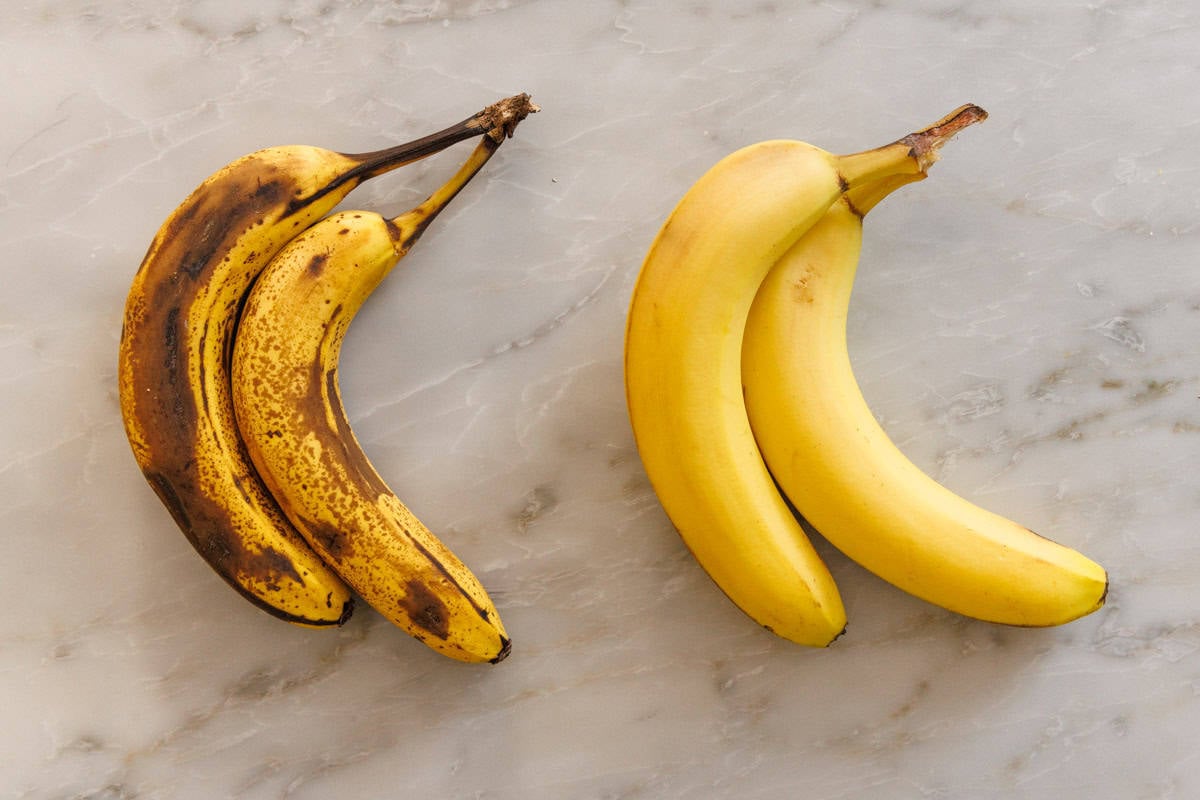 A comparison photos os bananas showing two that are spotty and ripe and two that are yellow and not as ripe.