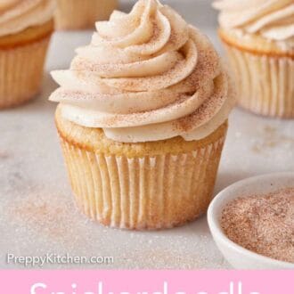 Pinterest graphic of a snickerdoodle cupcake with a bowl of cinnamon sugar beside it. More cupcakes in the background.