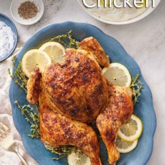 Pinterest graphic of an overhead view of a blue platter of spatchcock chicken with lemon slices and fresh thyme. A bowl of mashed potatoes on the side with salt and pepper.