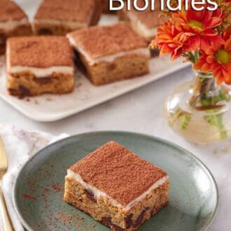 Pinterest graphic of a green plate with a piece of tiramisu blondie. Flowers and a platter of more tiramisu blondies in the background.