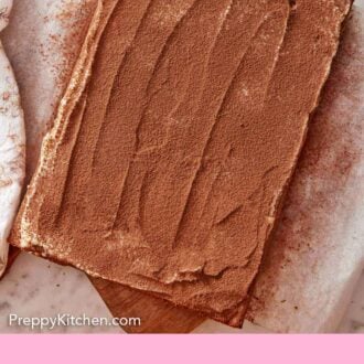 Pinterest graphic of an overhead view of an uncut slab of tiramisu blondies with cocoa powder dusted on top.