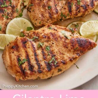 Pinterest graphic of a close up view of a cilantro lime chicken breast on a platter with more chicken along with cut limes and cilantro garnish.