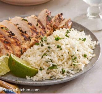 Pinterest graphic of a plate of cilantro lime rice with sliced chicken breast and cut limes.