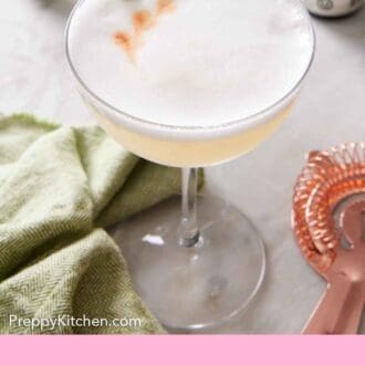 Pinterest graphic of a glass of pisco sour with a lime twist with dashes of bitters on top.