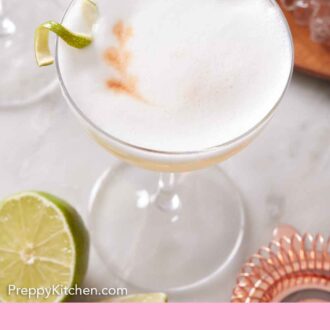 Pinterest graphic of a slightly overhead view of a glass of pisco sour with a lime garnish.