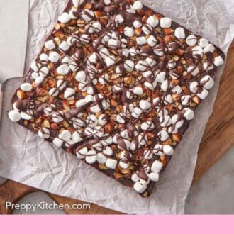 Pinterest graphic of an uncut slab of rocky road bars on a parchment lined serving board.