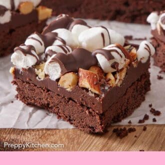 Pinterest graphic of a cut piece of rocky road bars with the rest of the dessert in the background.