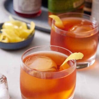 Pinterest graphic of two glasses of Vieux Carré cocktails with lemon peel garnish.