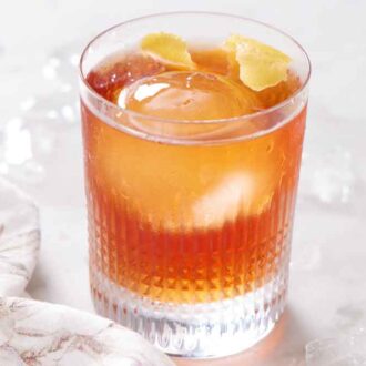 A glass of Vieux Carré with a round ice cube and lemon peel garnish.