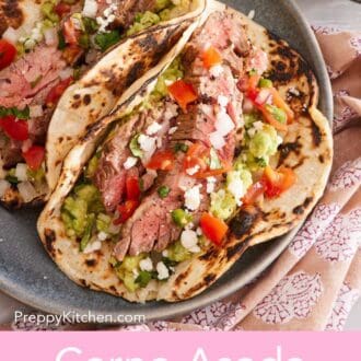 Pinterest graphic of two carne asada tacos with chopped cilantro and crumbled cheese as garnish.