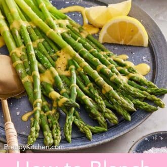Pinterest graphic of a platter of blanched asparagus with sauce drizzled on top and lemon wedges on the side.