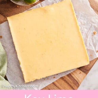 Pinterest graphic of an overhead view of an uncut slab of key lime pie bars on a parchment lined serving board along with a bowl of key limes.