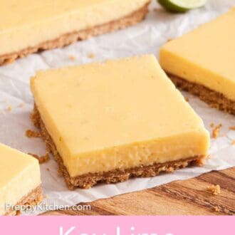 Pinterest graphic of sliced key lime pie bars on a parchment lined board with the rest of the uncut dessert in the background.