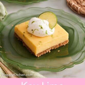 Pinterest graphic of a key lime pie bar on a green plate topped with whipped cream, lime zest, and a lime wheel.