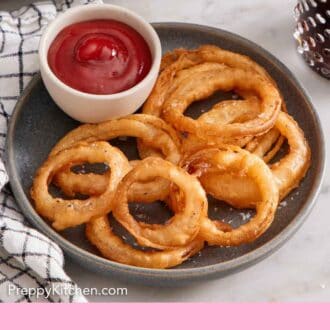 Pinterest graphic of a plate of onion rings with onion rings with a bowl of ketchup.