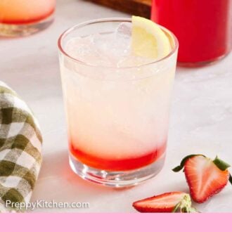 Pinterest graphic of a drink with strawberry syrup on the bottom and lemon garnish.