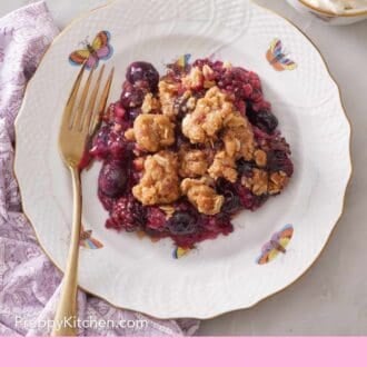 Pinterest graphic showing triple berry crisp on a small serving plate with a fork.