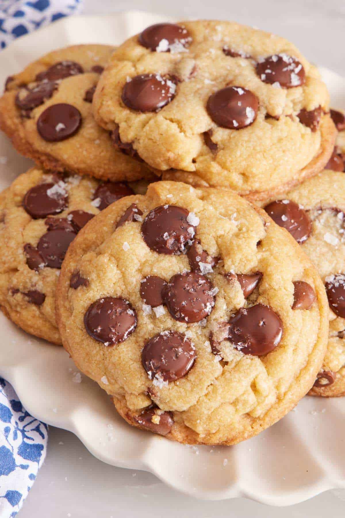 Brown butter cookies piled on a plate with sea salt sprinkled on top.