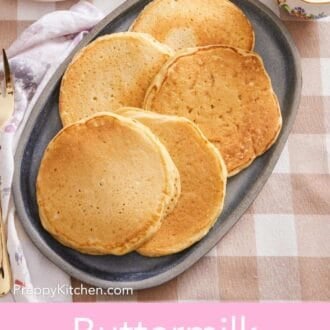 Pinterest graphic showing an overhead shot of several fluffy pancakes on a serving platter with syrup and berries on the side.