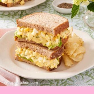 Pinterest graphic showing egg salad sandwich on a plate with potato chips.