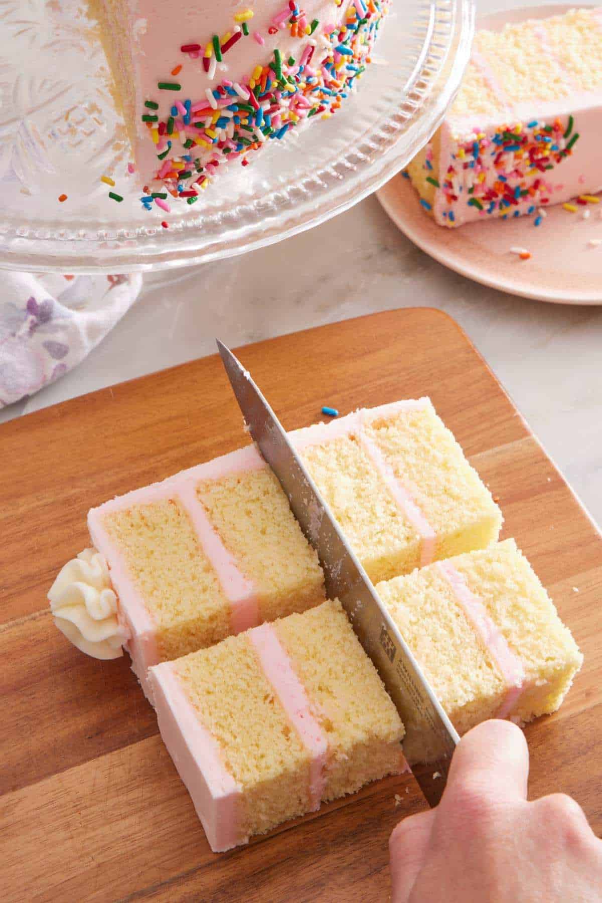 A slice of cake with pink frosting cut into four squares.