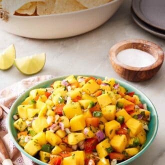 Pinterest graphic showing a bowl of mango salsa with tortilla chips in the background.