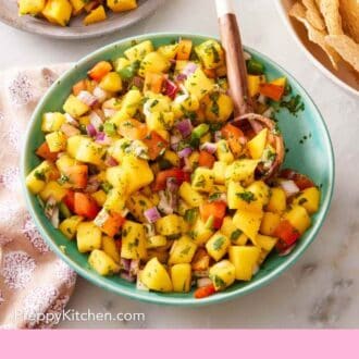 Pinterest graphic showing an overhead shot of salsa with mango in a green bowl with a wooden spoon.