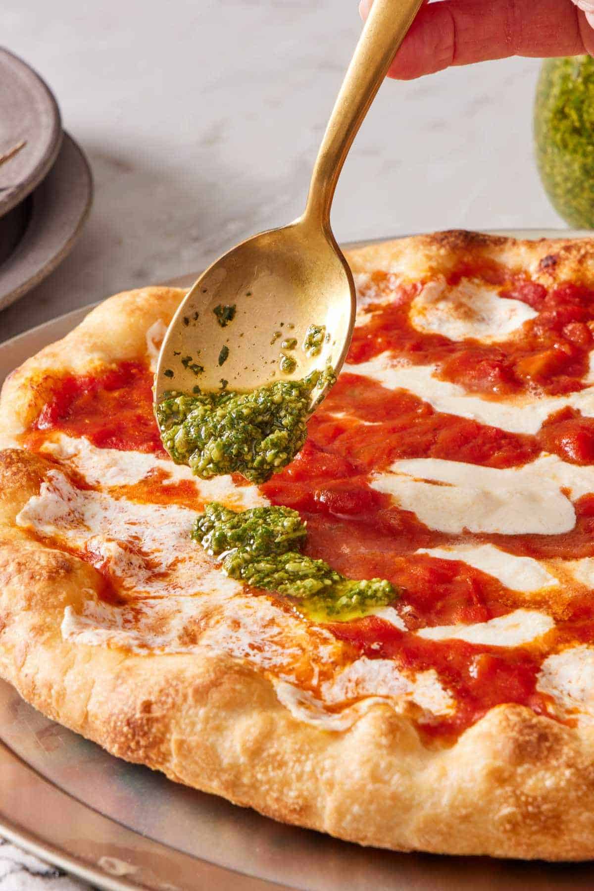 Basil condiment spooned onto a pizza.