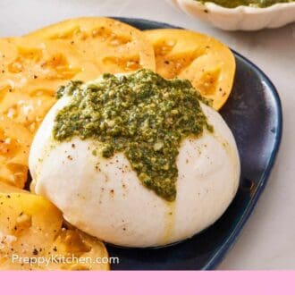 Pinterest graphic showing burrata cheese topped with homemade pesto with sliced tomatoes on the side.