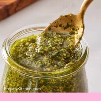 Pinterest graphic showing a close-up of a green basil-based Italian sauce in a small glass jar.
