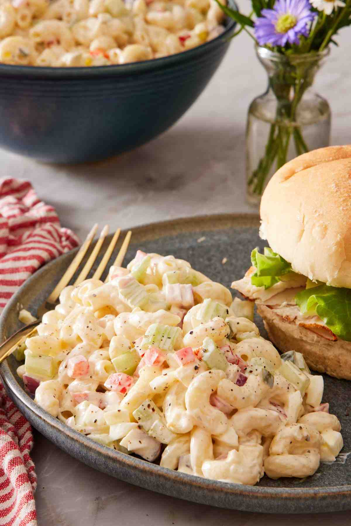 Pasta salad with mayo dressing on a plate with a burger.