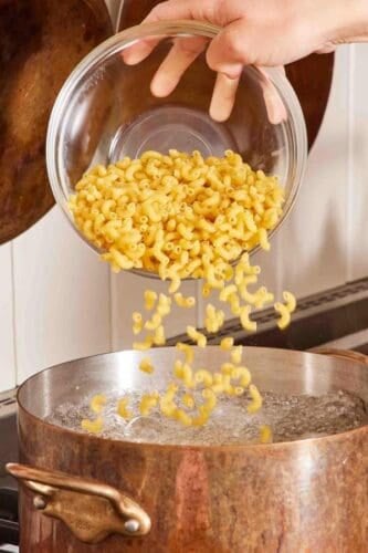 Macaroni dropped into a pot of boiling water.