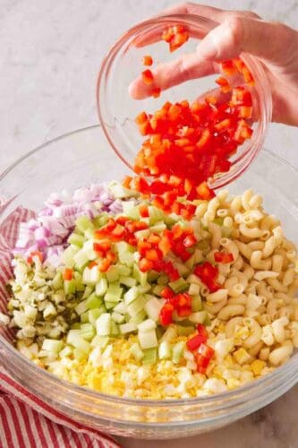Macaroni salad ingredients combined in a large glass bowl.