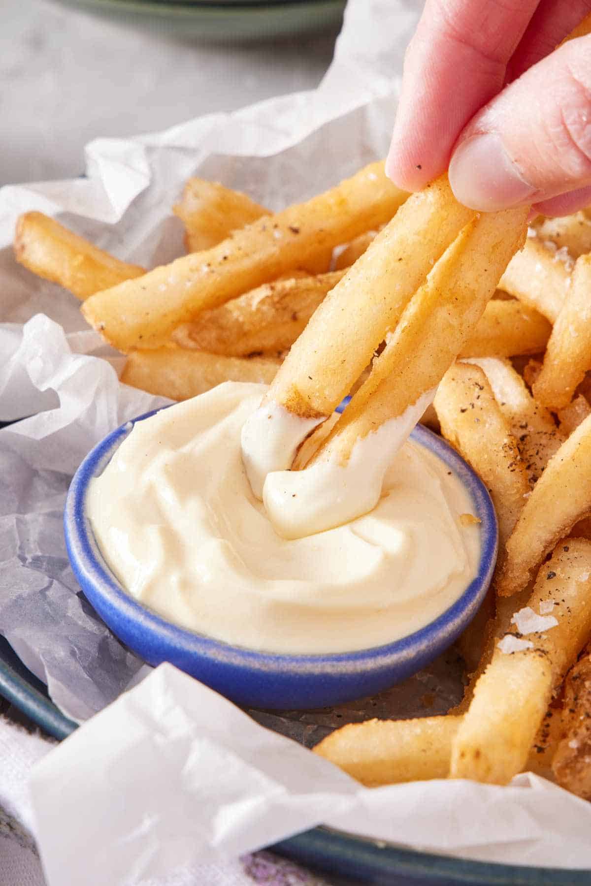 Fries dipped into a small bowl of mayonnaise.