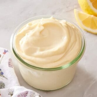 Close-up of a jar of mayo with lemon wedges next to it.