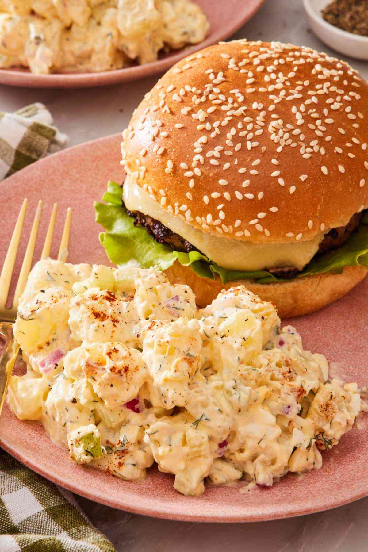 Potato salad and a burger on a plate with a fork.