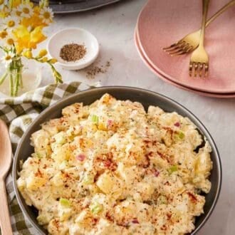 Pinterest graphic showing a serving bowl of potato salad with burgers, black pepper, and plates in the background.