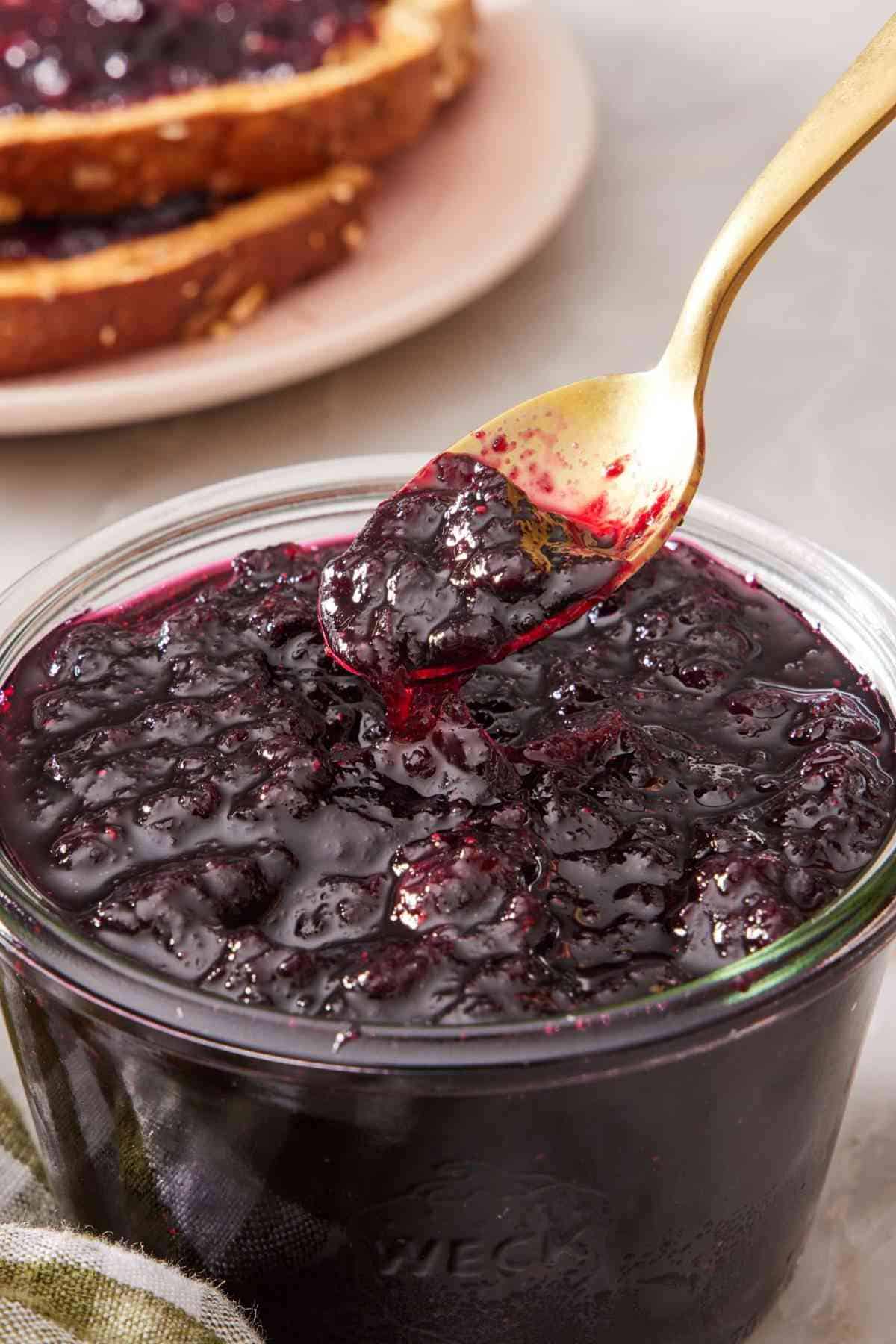 Close up of homemade blueberry jam with a spoon dipped in.