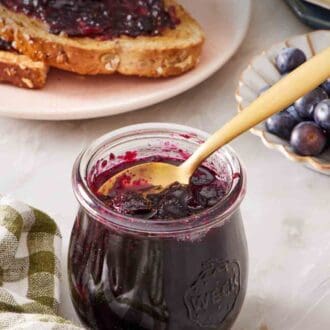 Pin image showing a small jar of jam with toasted jam spread with jam in the background.