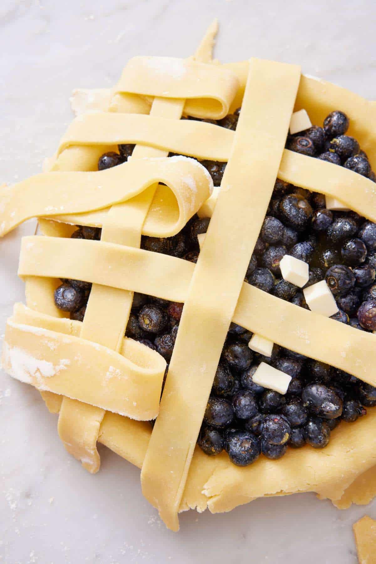 Image depicting how to make a lattice crust on an unbaked blueberry pie.