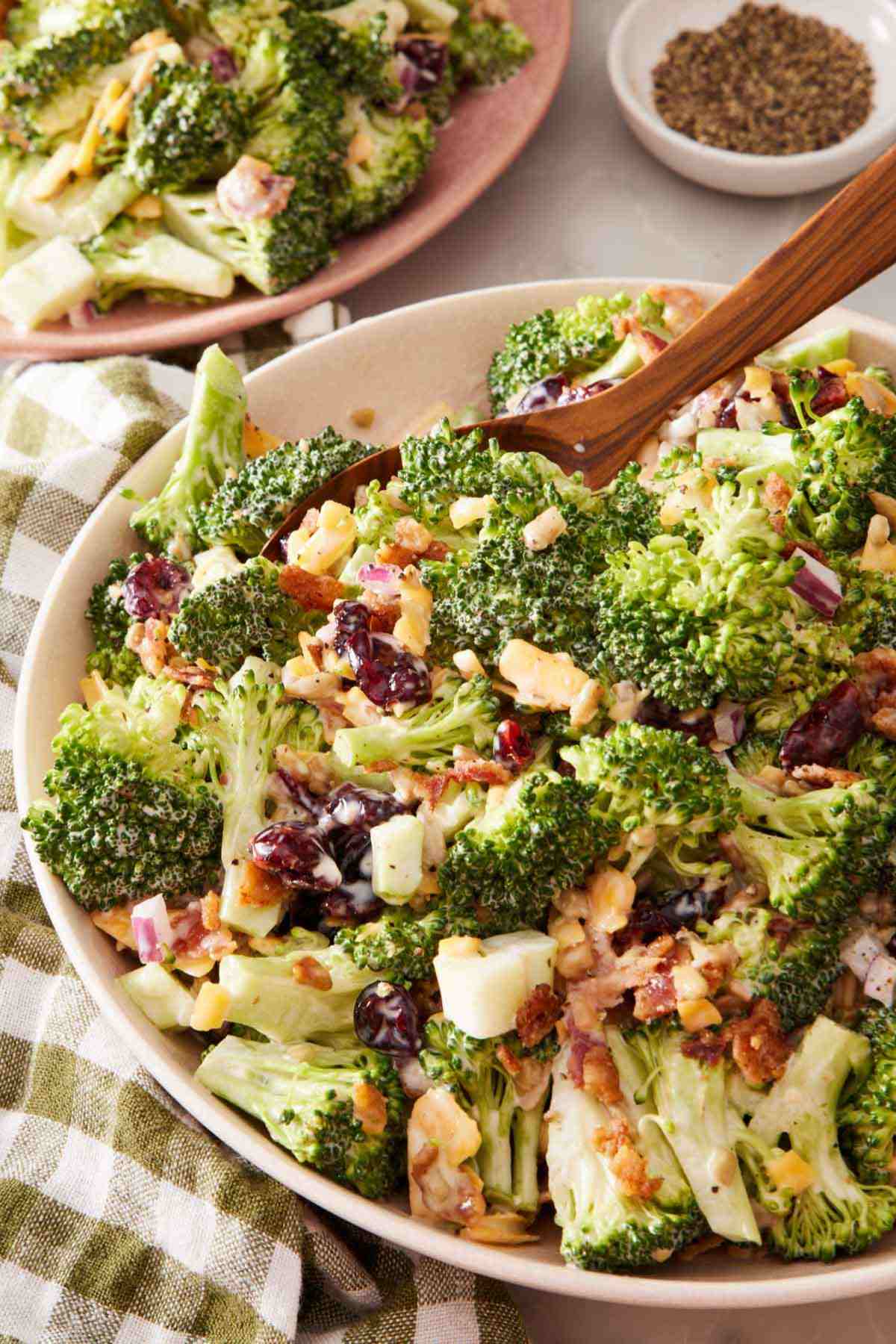 Close up of broccoli salad in a large bowl with a wooden spoon.