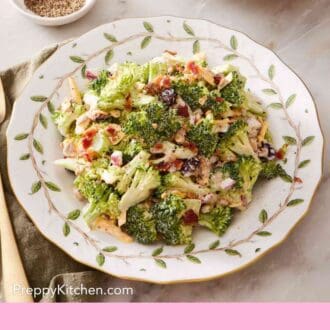 Pinterest graphic showing an overhead shot of broccoli salad on a white plate with a leaf pattern.