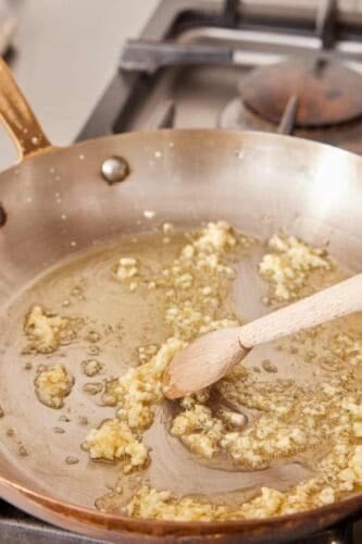 Garlic and olive oil heating in a skillet.