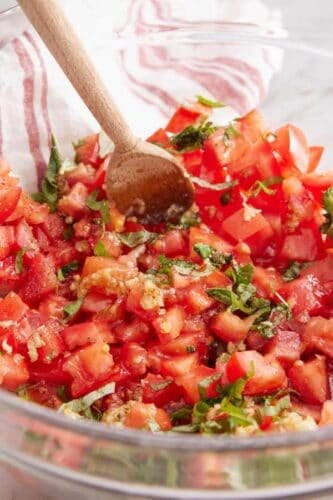 Tomato topping mixed together with a wooden spoon.
